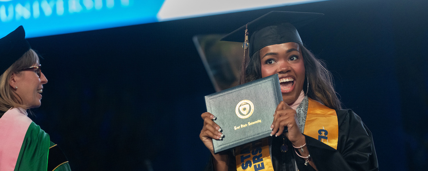 A new  graduate smiles as she holds her diploma during her commencement ceremony. (Photo credit: Bob Christy, )