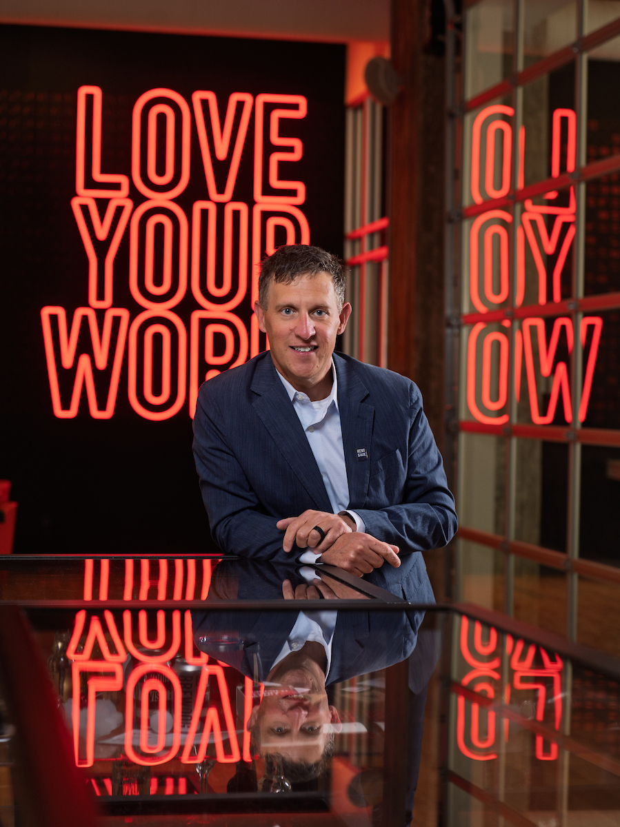 Matt Heisey sitting in front of a sign that says Love Your Work in the Vocon Cleveland office