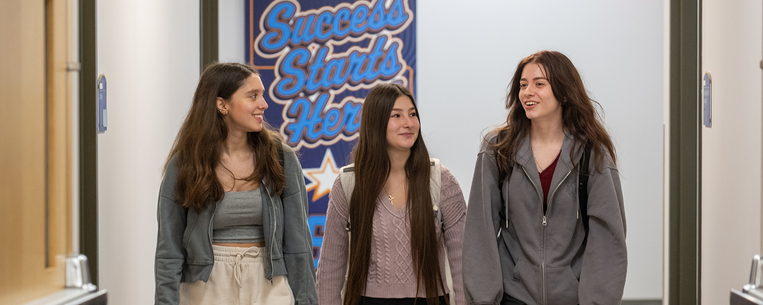 Three female students walk in front of a Success Starts Here sign on the Ashtabula Campus