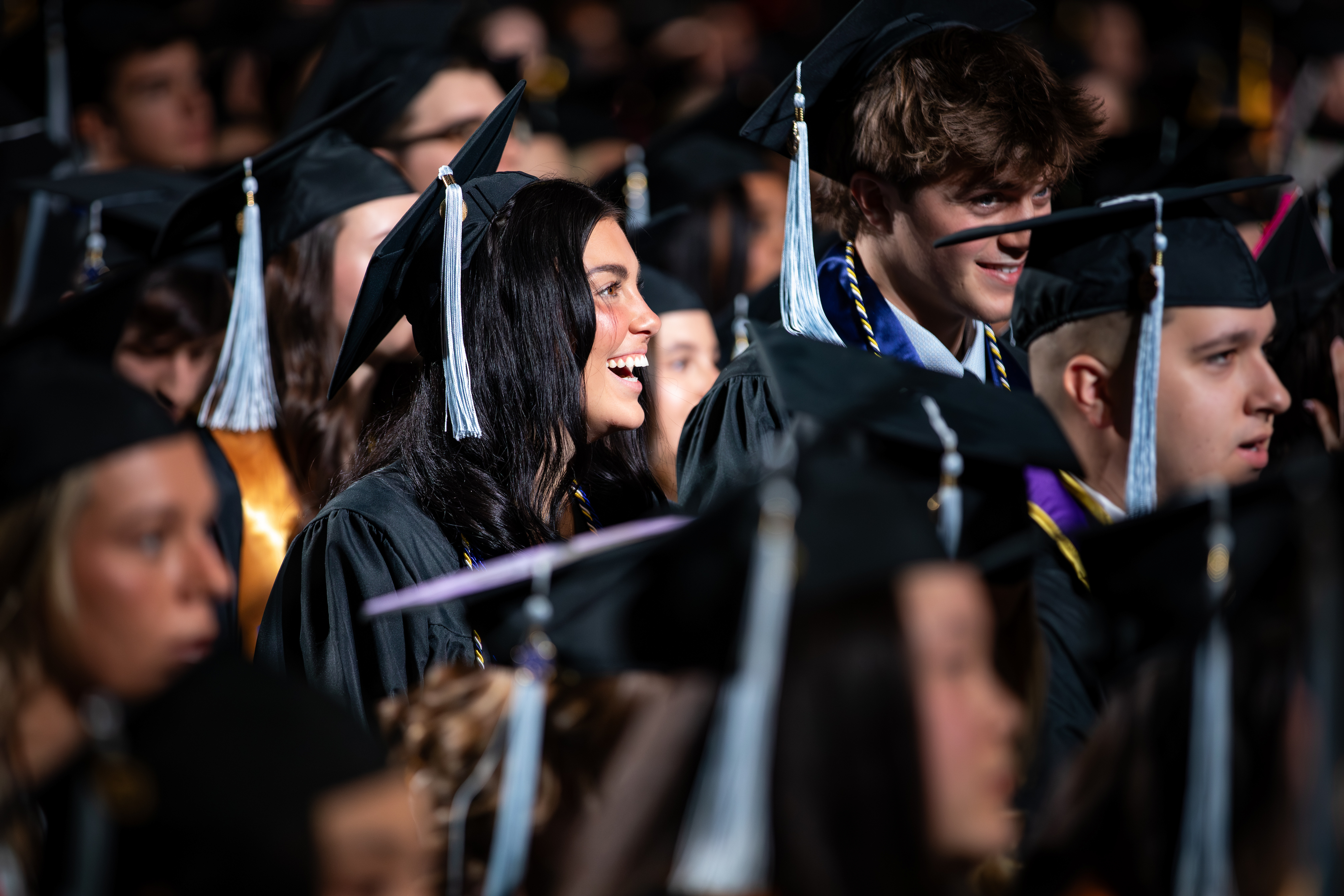 Students smiling in the crowd during commencement.