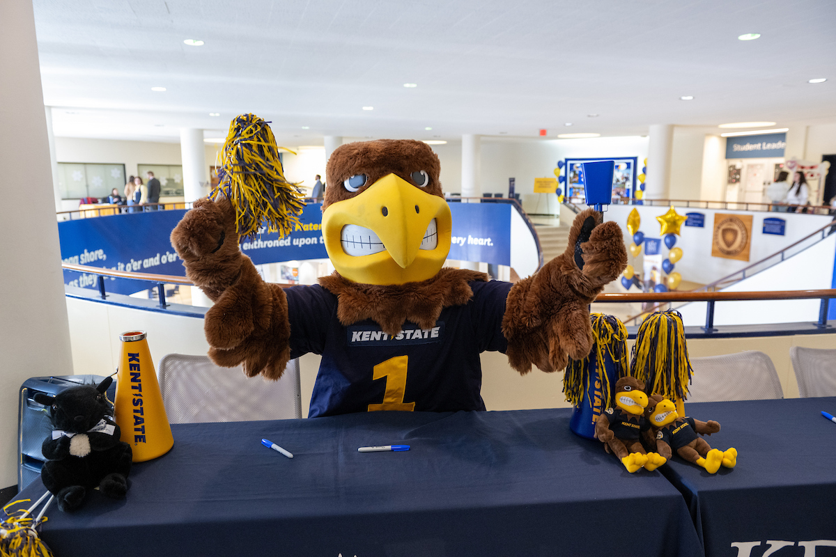 Mascot Flash sits at a table with arms raised in celebration.