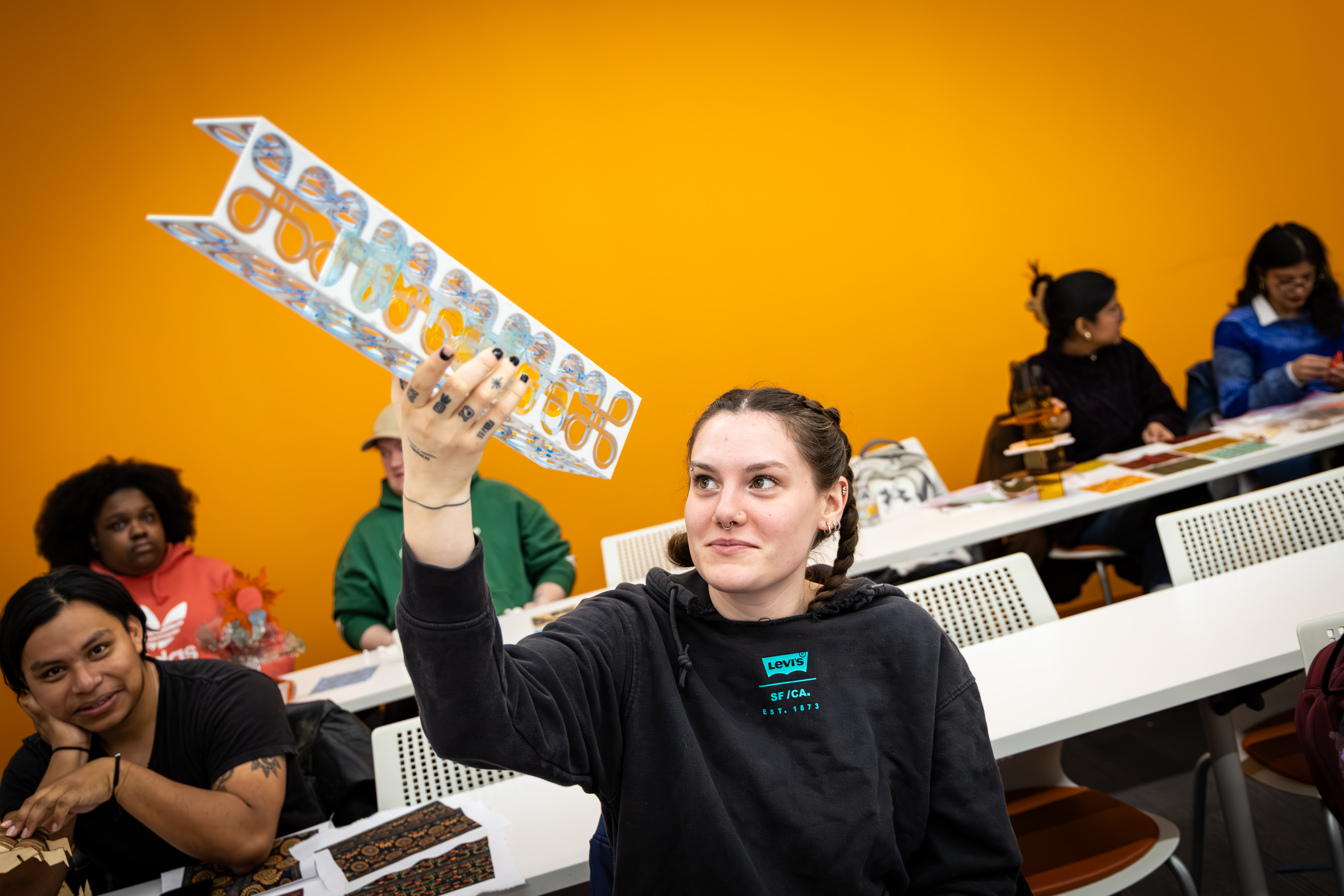 Student in Furman's workshop holding up their project looking at it