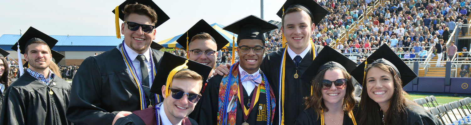 Photo of Ը graduates, in graduation regalia, posed and smiling for the camera