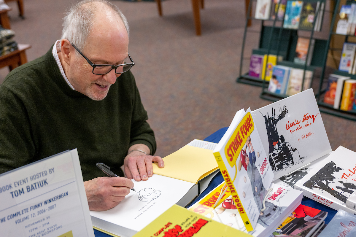 Cartoonist Tom Batiuk signs a copy of his Funky Winkerbean books at the Kent State University Book Store.