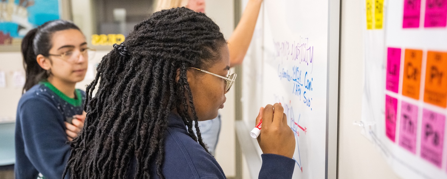 Students writing on a white board