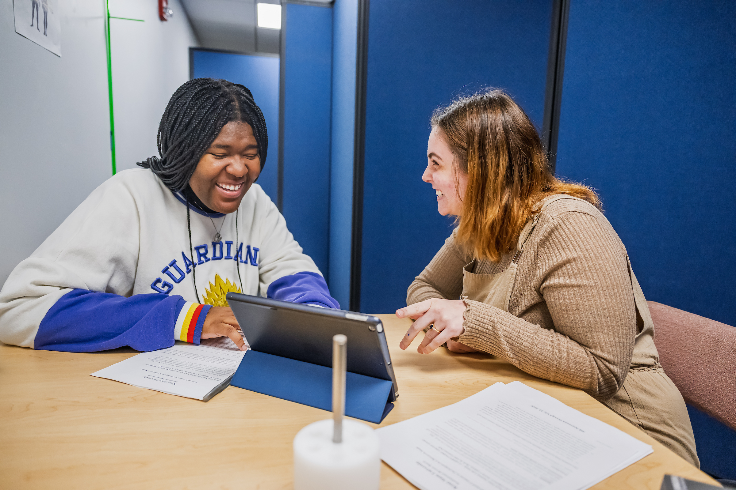 A student sitting at a table with a tutor
