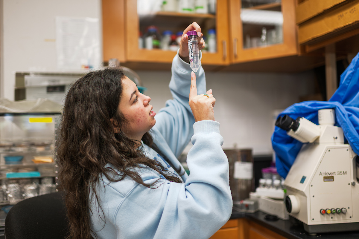 Student researcher testing river water in a lab
