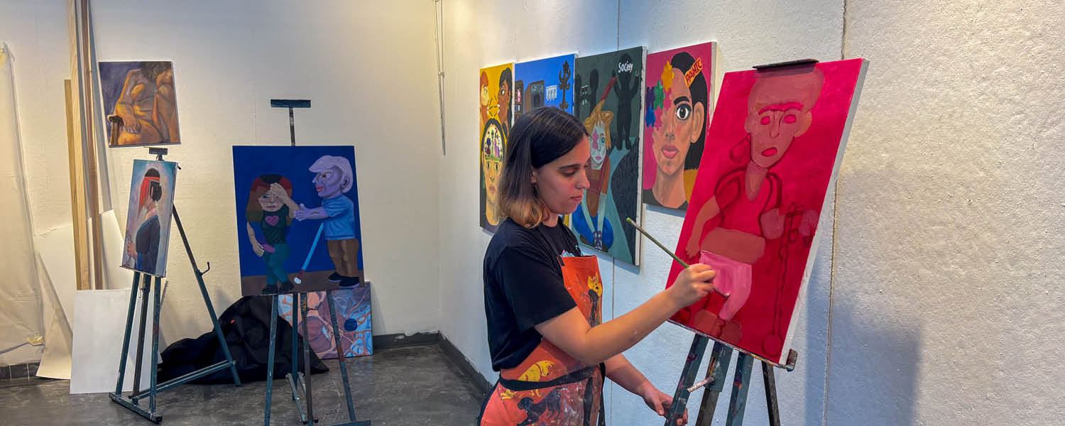 Artist paints on a canvas with bright reds