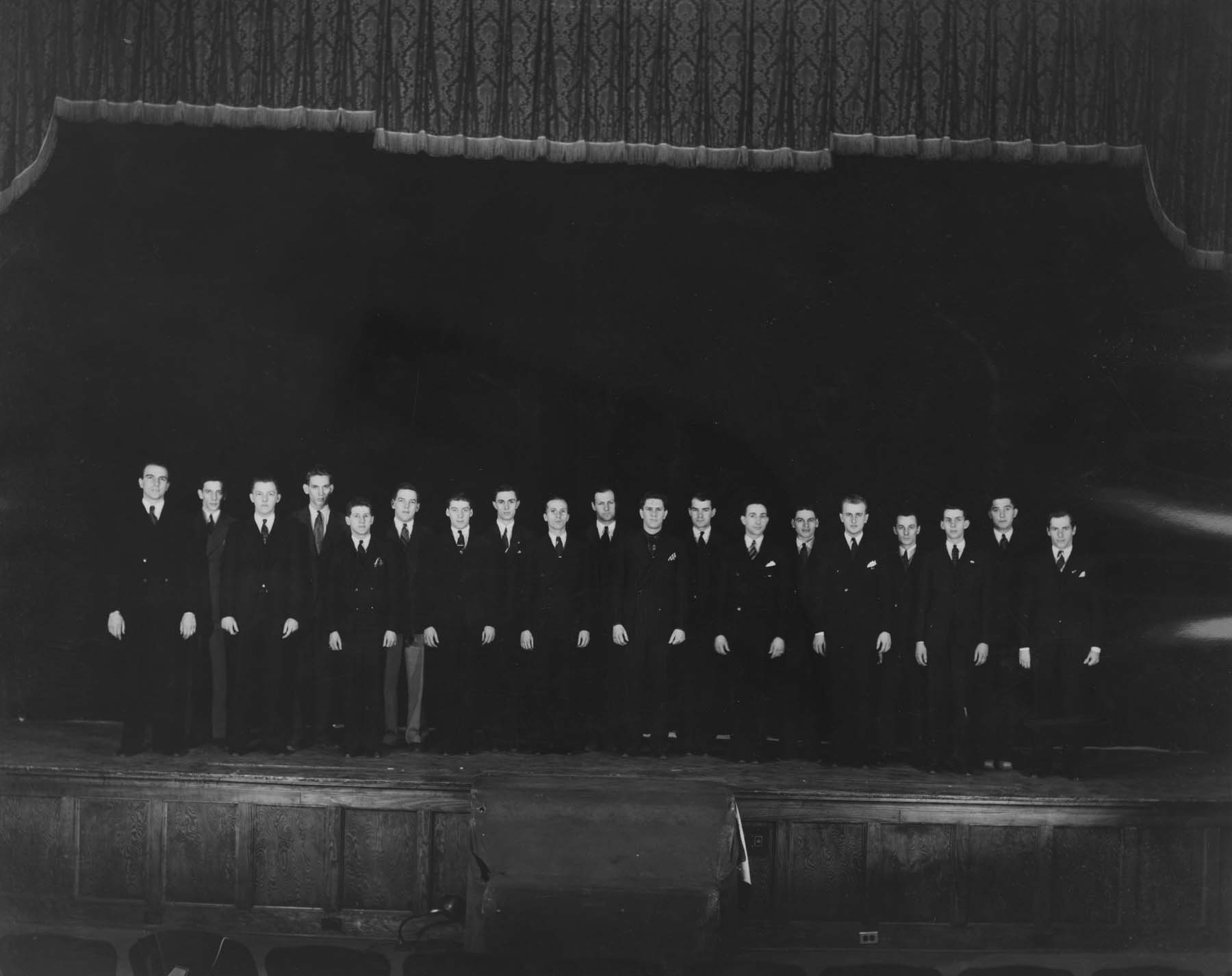 Members of the Men’s Glee Club, directed by Bruce Handley, stand on stage in a photo that appears on page 70 of the 1939 Chestnut Burr. The first concert given by a men’s glee club at Kent State College was in 1929, with 19 members. The first full program by the glee club took place in 1934, with Fred Denker directing 25 members.