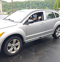 A happy grad waves from her car A happy grad waves from her car