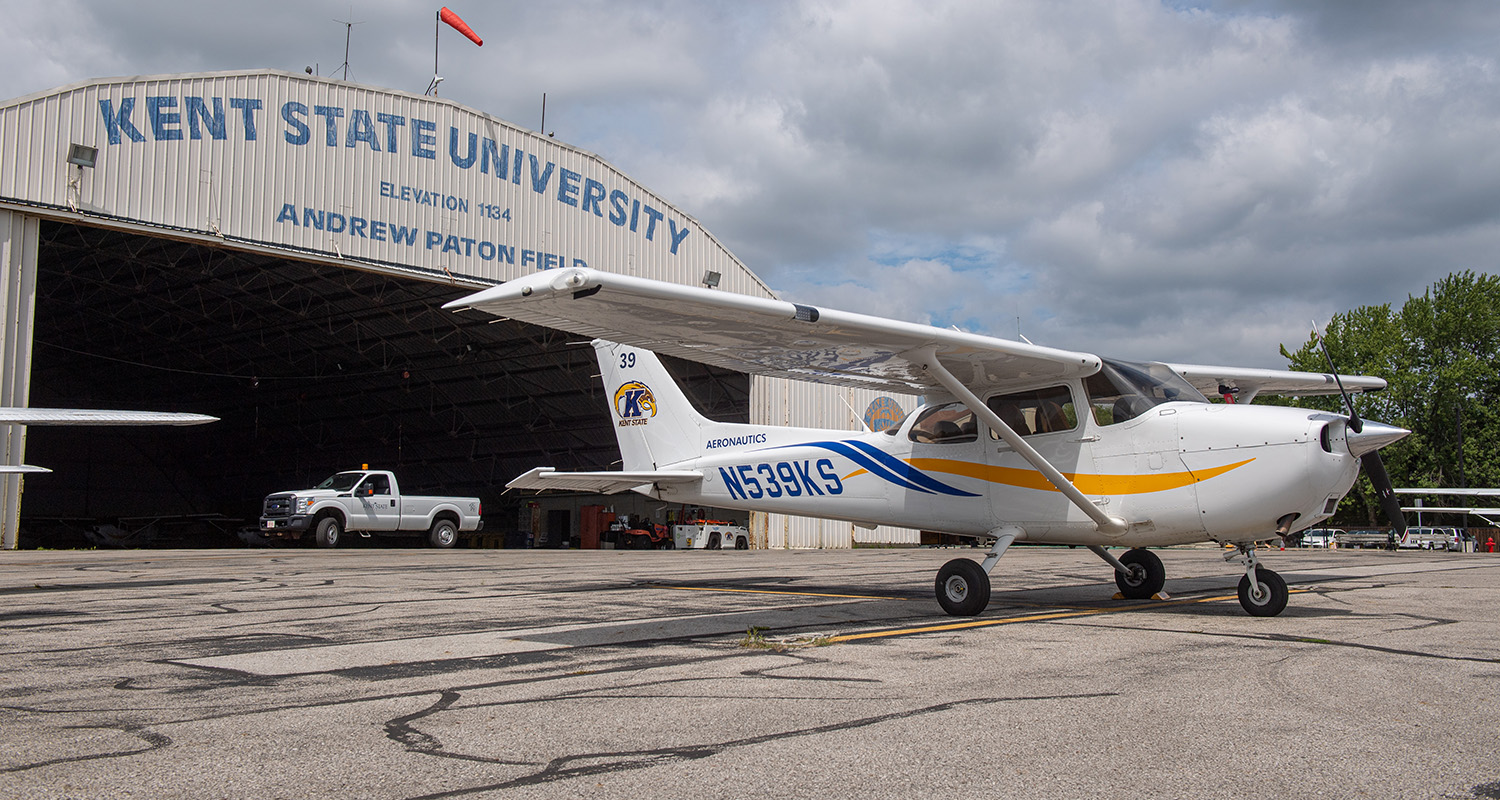 A single-engine airplane parked outside a hangar.