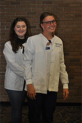 Senior BSN student Baylee McCandless presenting the white coat to Chloe Chappell