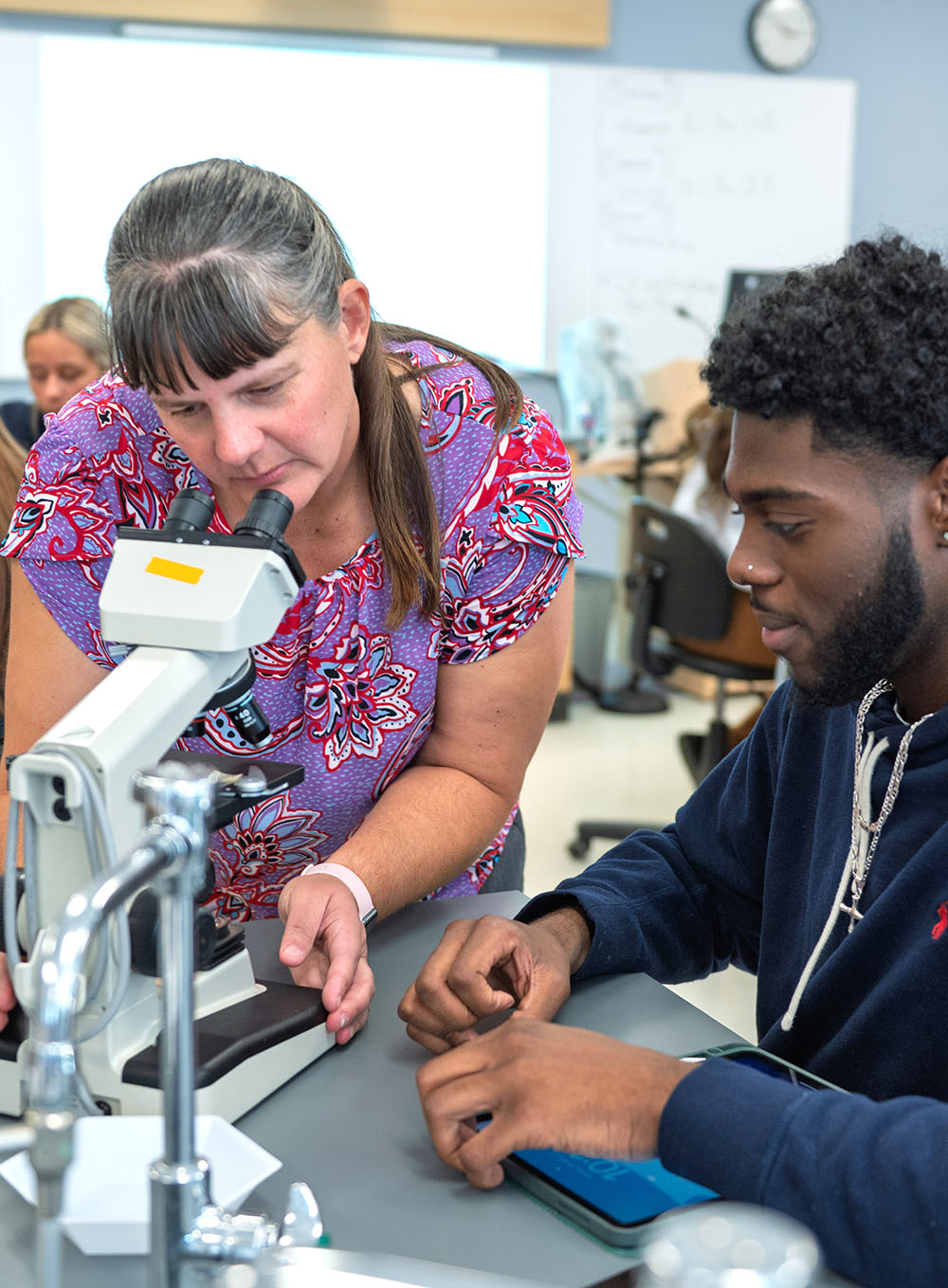An instructor assisting a student with a microscope in a science laboratory at the Kent State University Geauga Twinsburg Academic Center.