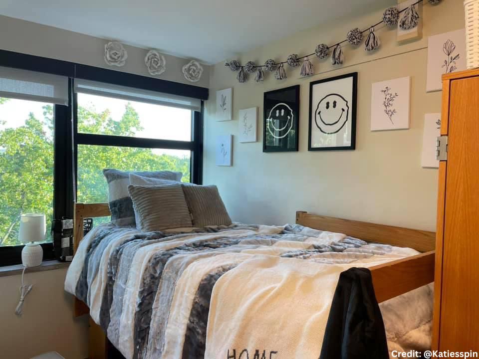 A dorm room with two black and white smiley face posters along with black and white decorations on the wall and bedding.