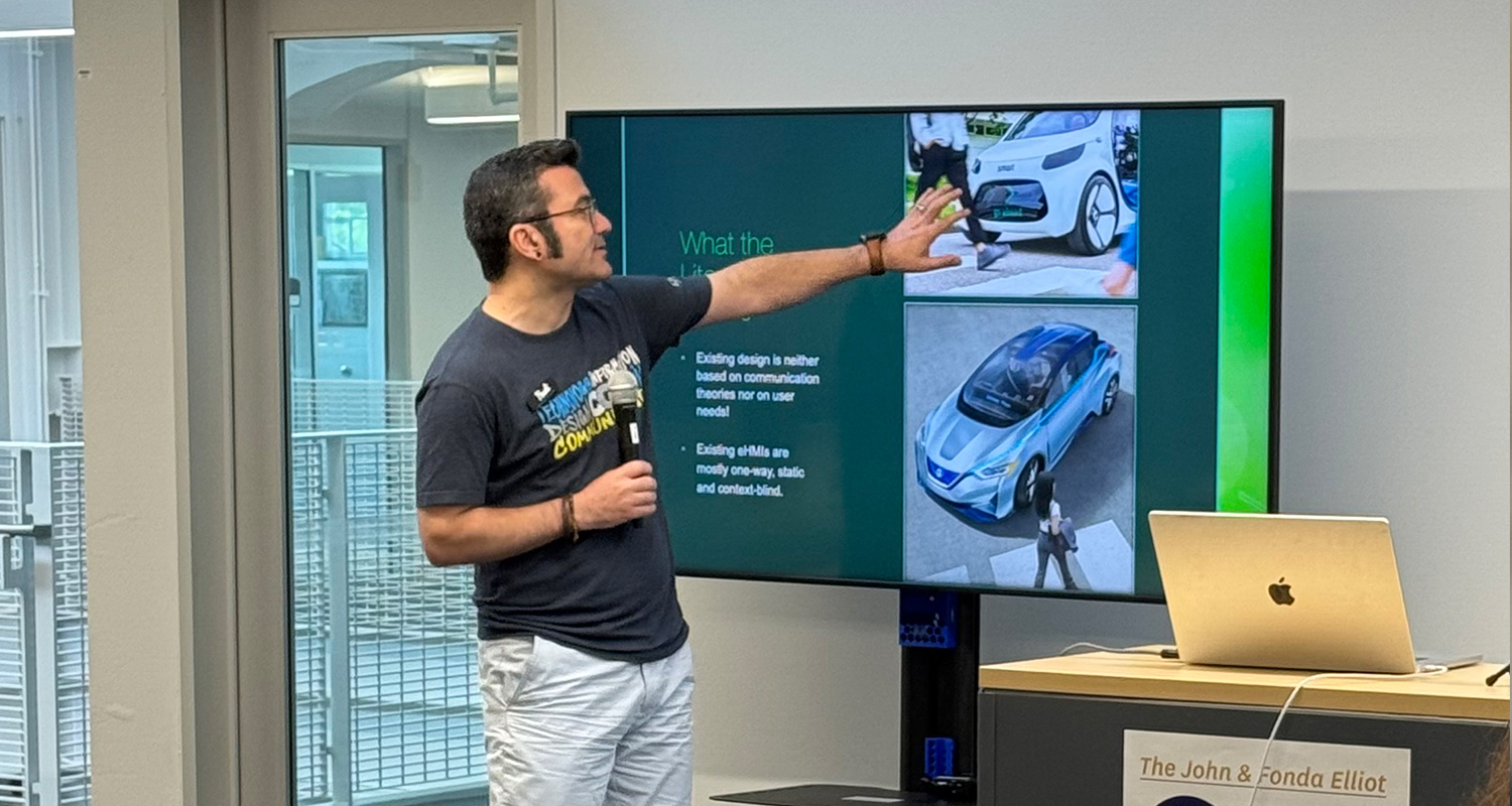 Design Innovation Fellow Hadi Rahmati points to large monitor and explains autonomous car feedback