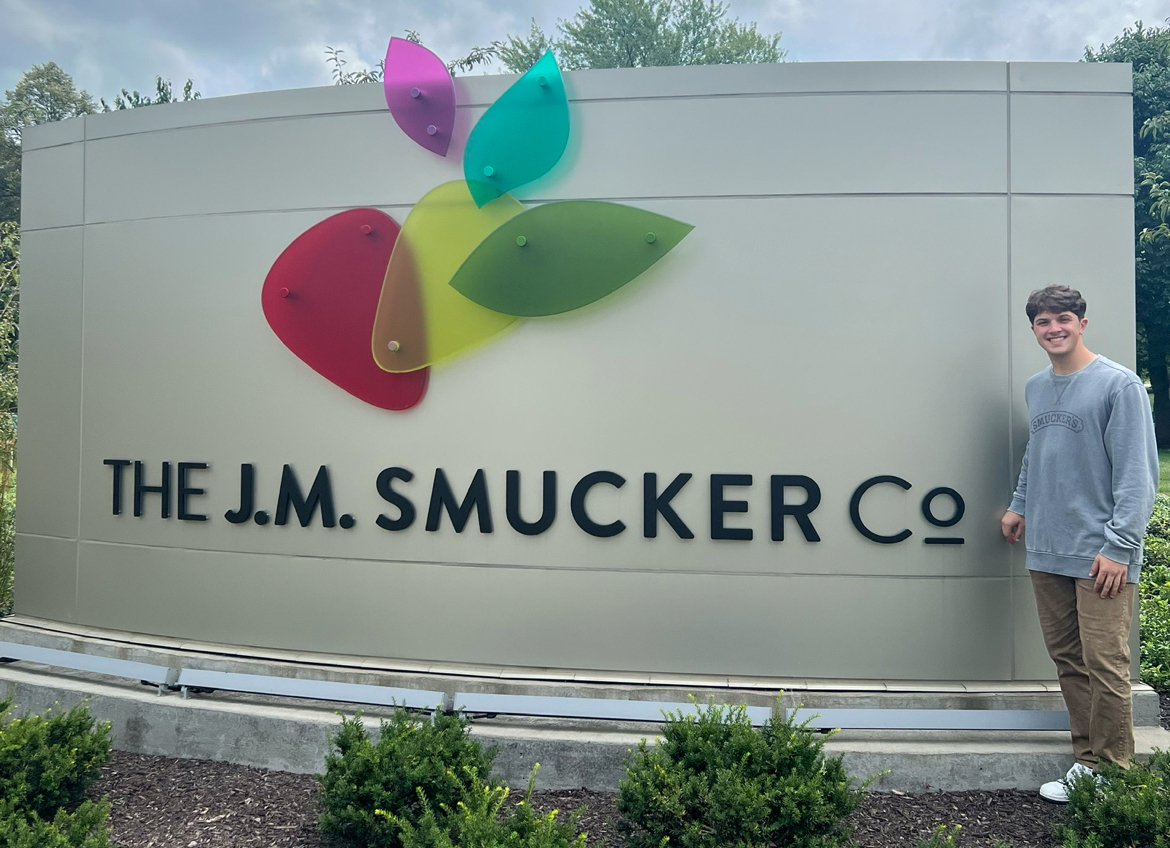 Drew stands next to The J.M. Smucker Company sign