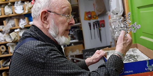 Artist Don Drumm in his studio holding a piece of metalwork.