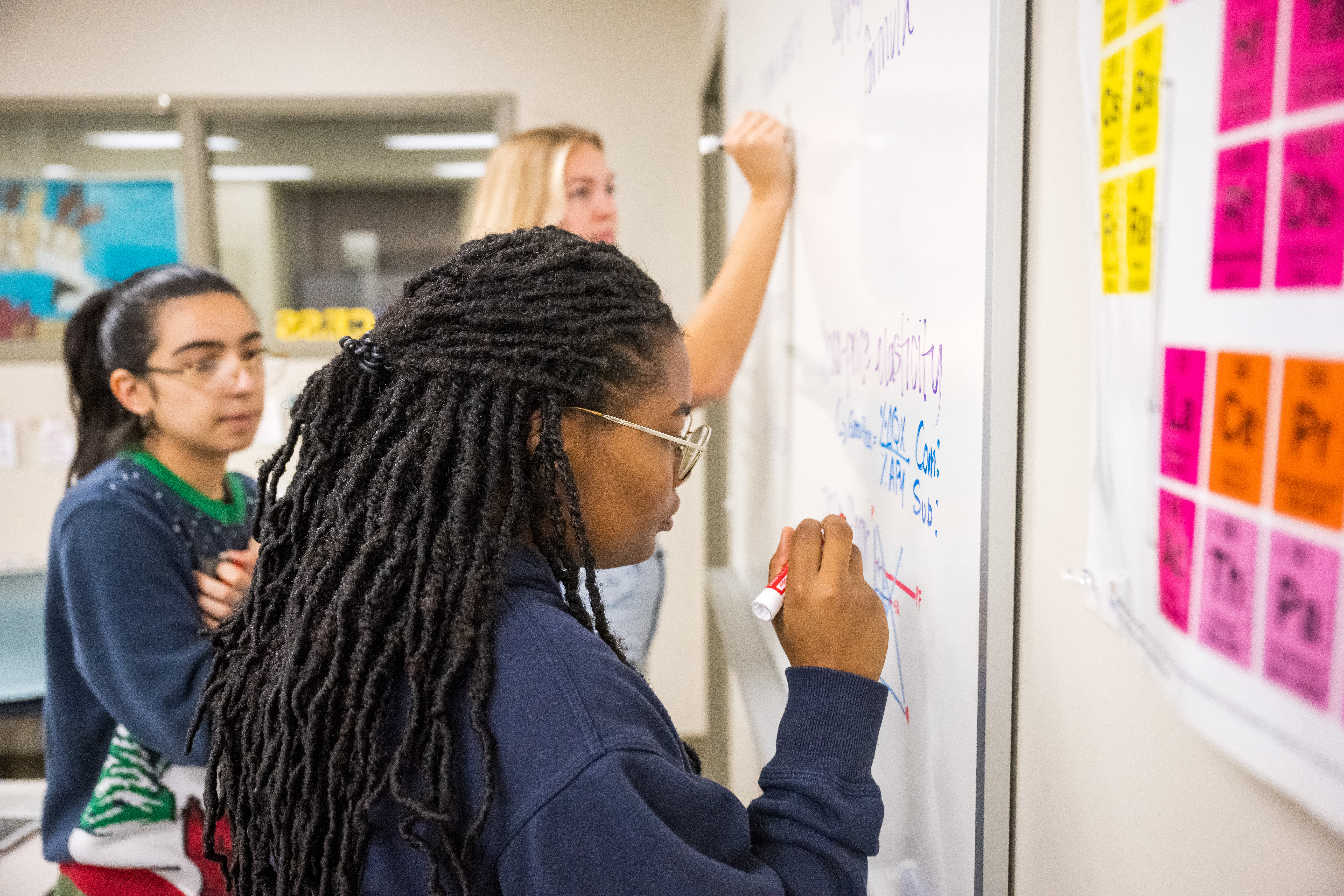Students writing on markerboard