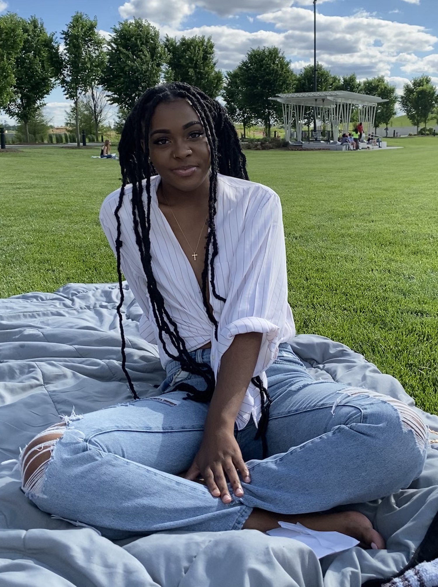 Taryn Phillips-Smith (March Student Leader of the Month) sits on a blanket in the grass.