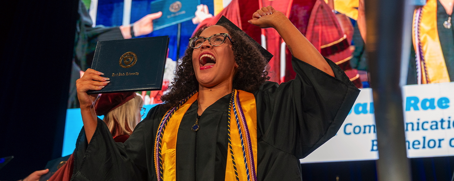A new Kent State graduate celebrates while holding her diploma