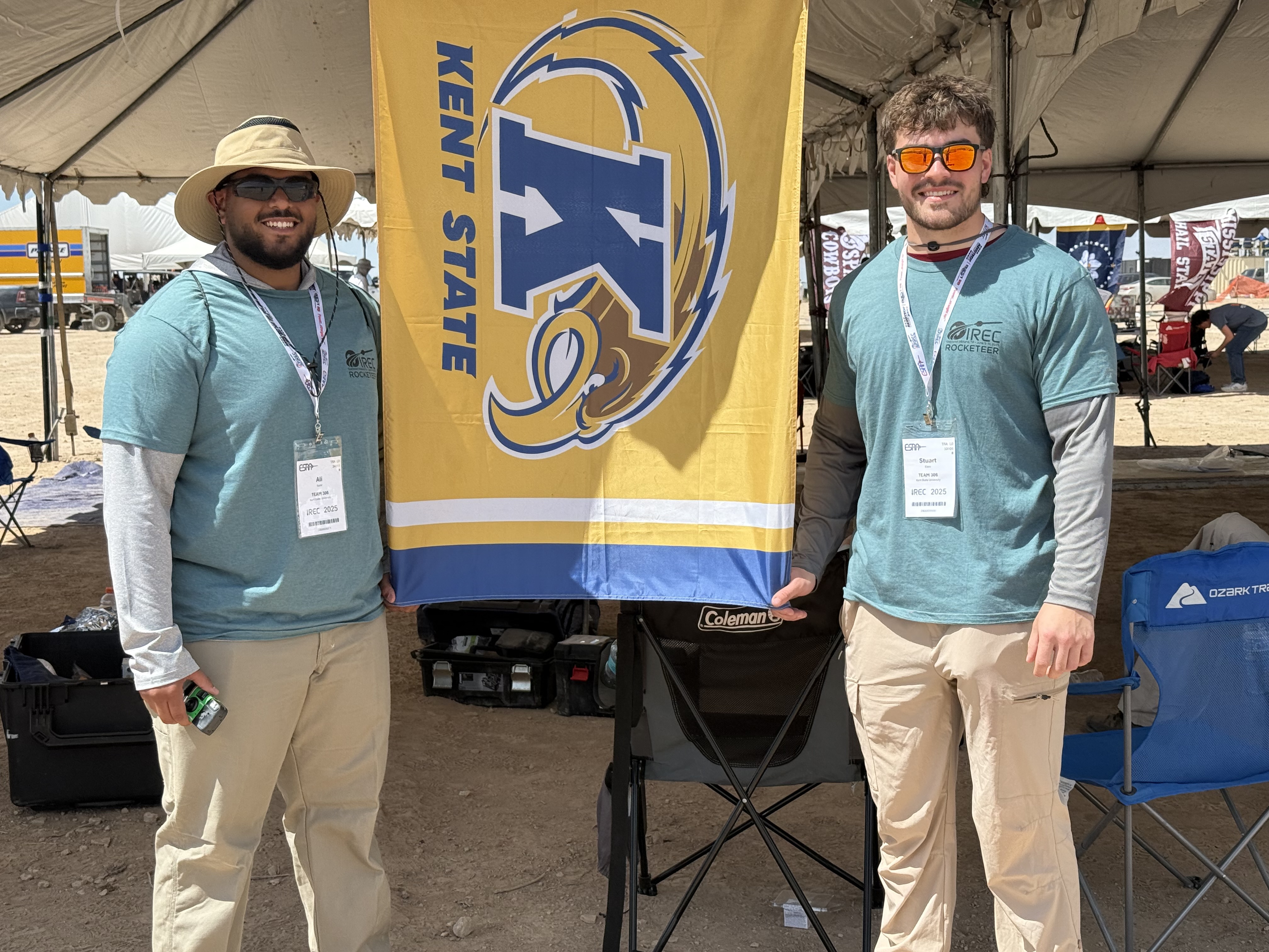Stuart standing with another student in front of �Ը������� flag.