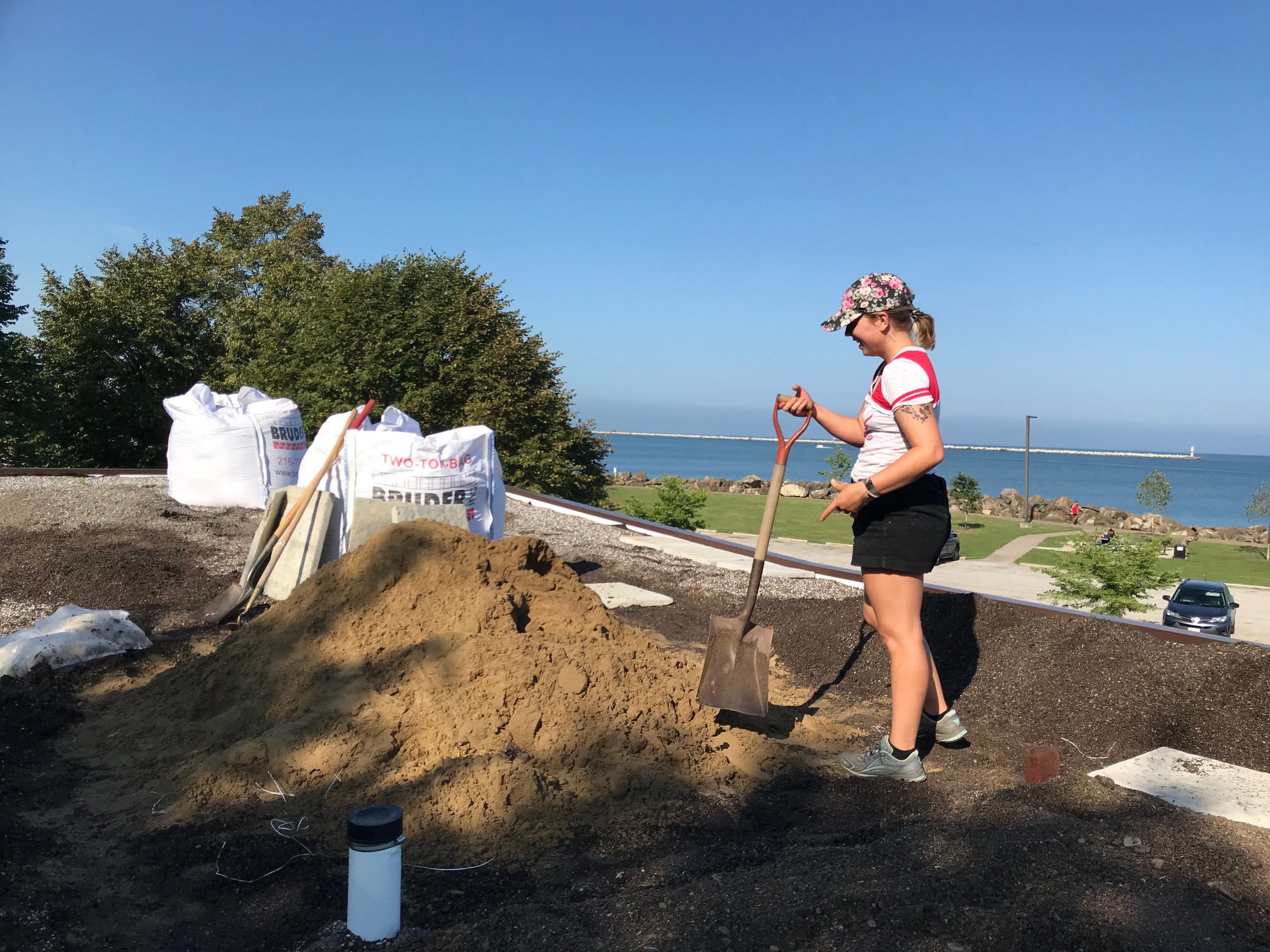 Student with shovel up on a roof with Lake Erie in background