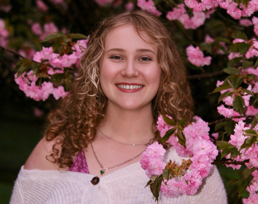 Madelyn Lands surrounded by pink flowers.
