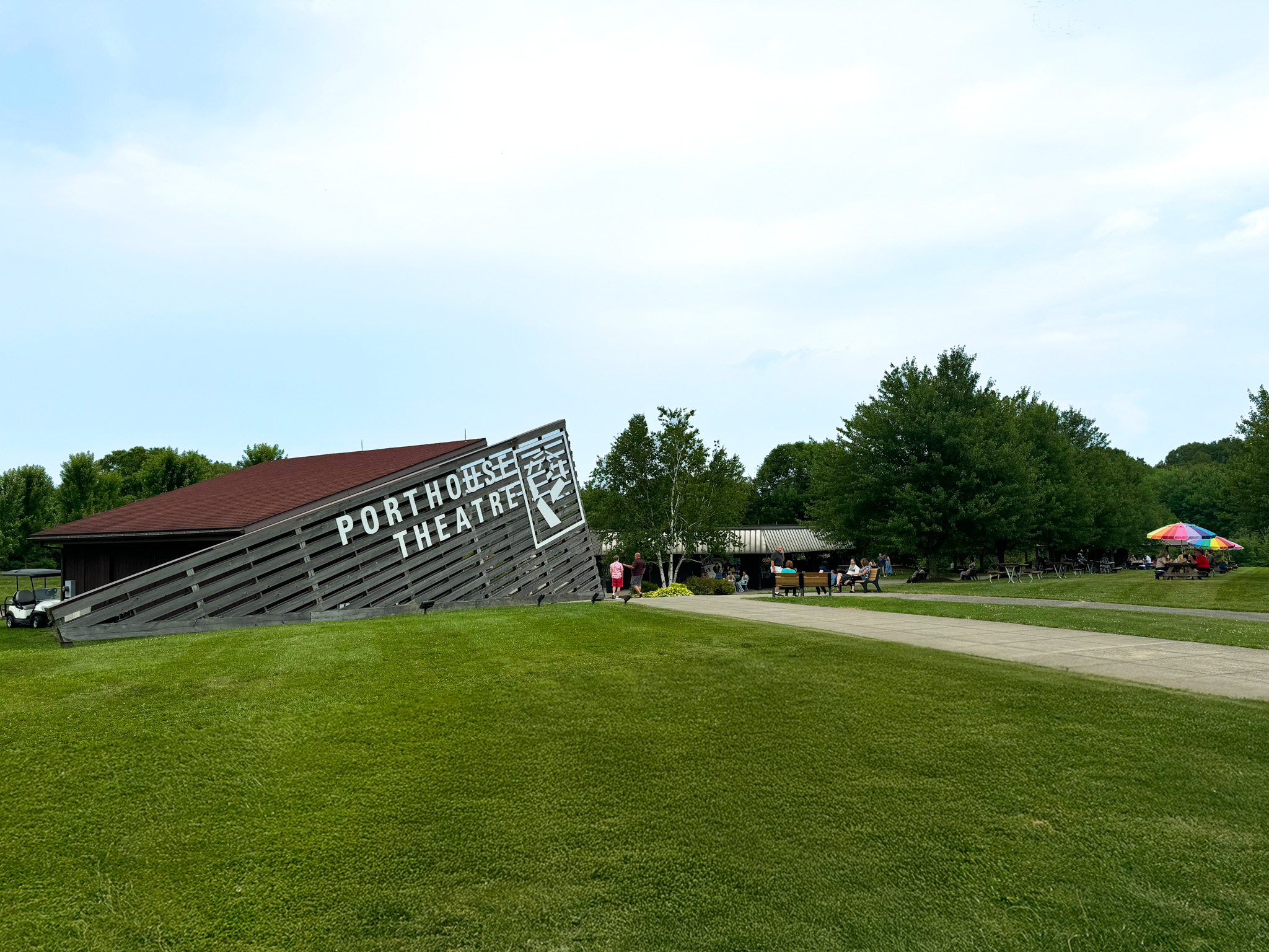 Porthouse Theatre Box Office building on a grass covered hill with a blue sky above. 