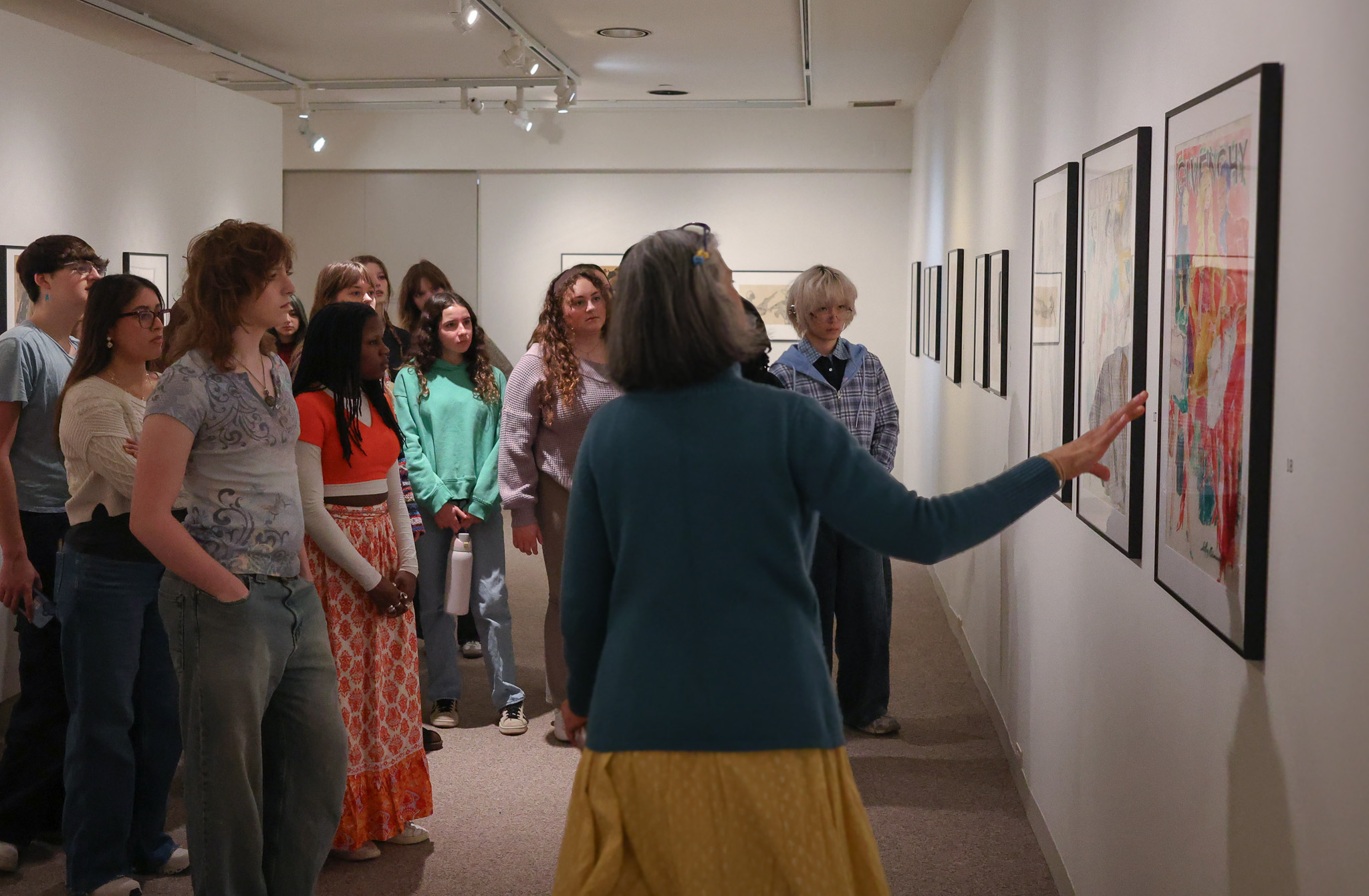Professor Archana Mehta pointing to Leroy Neiman exhibit artwork for students