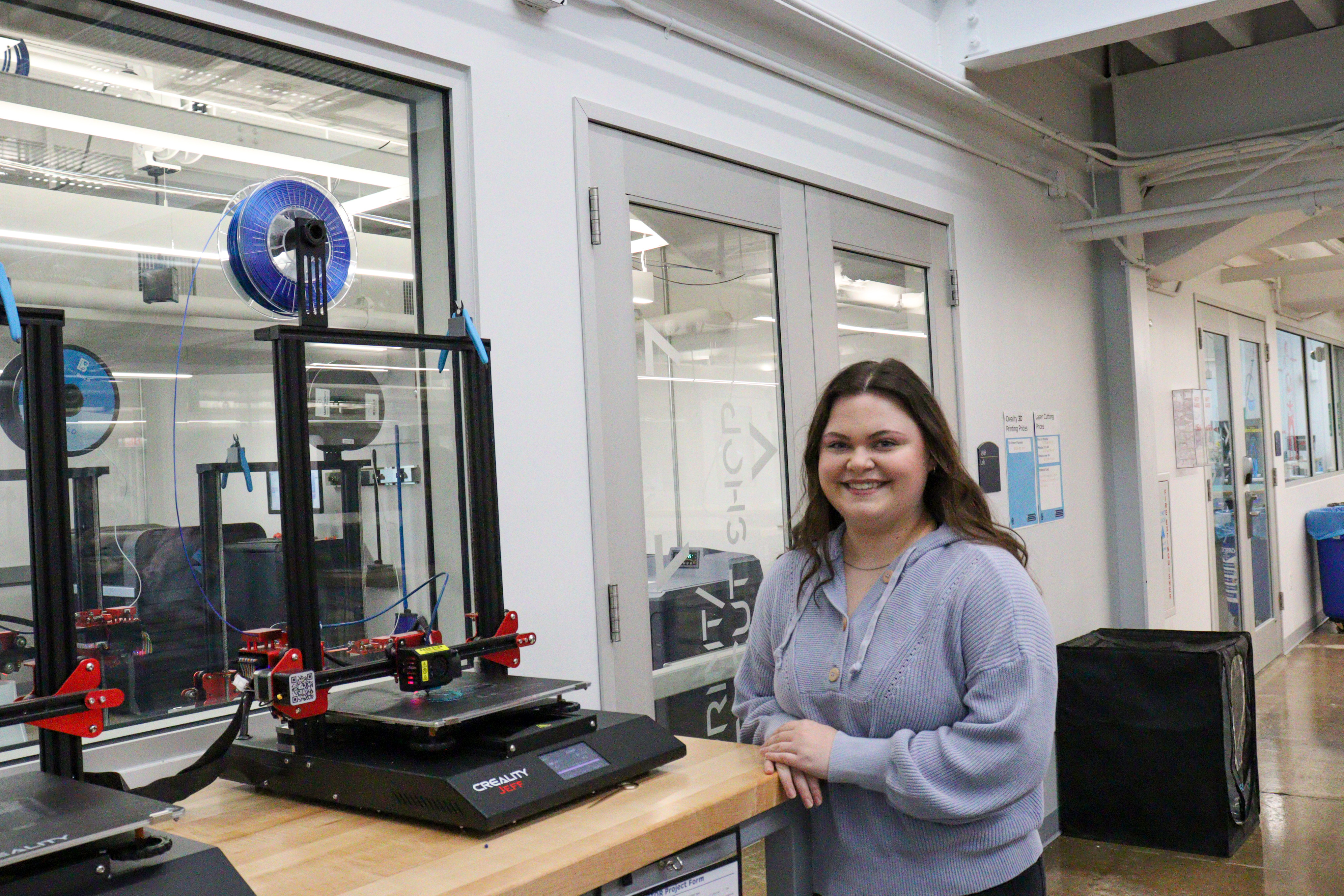 Student posing next to 3D Printer