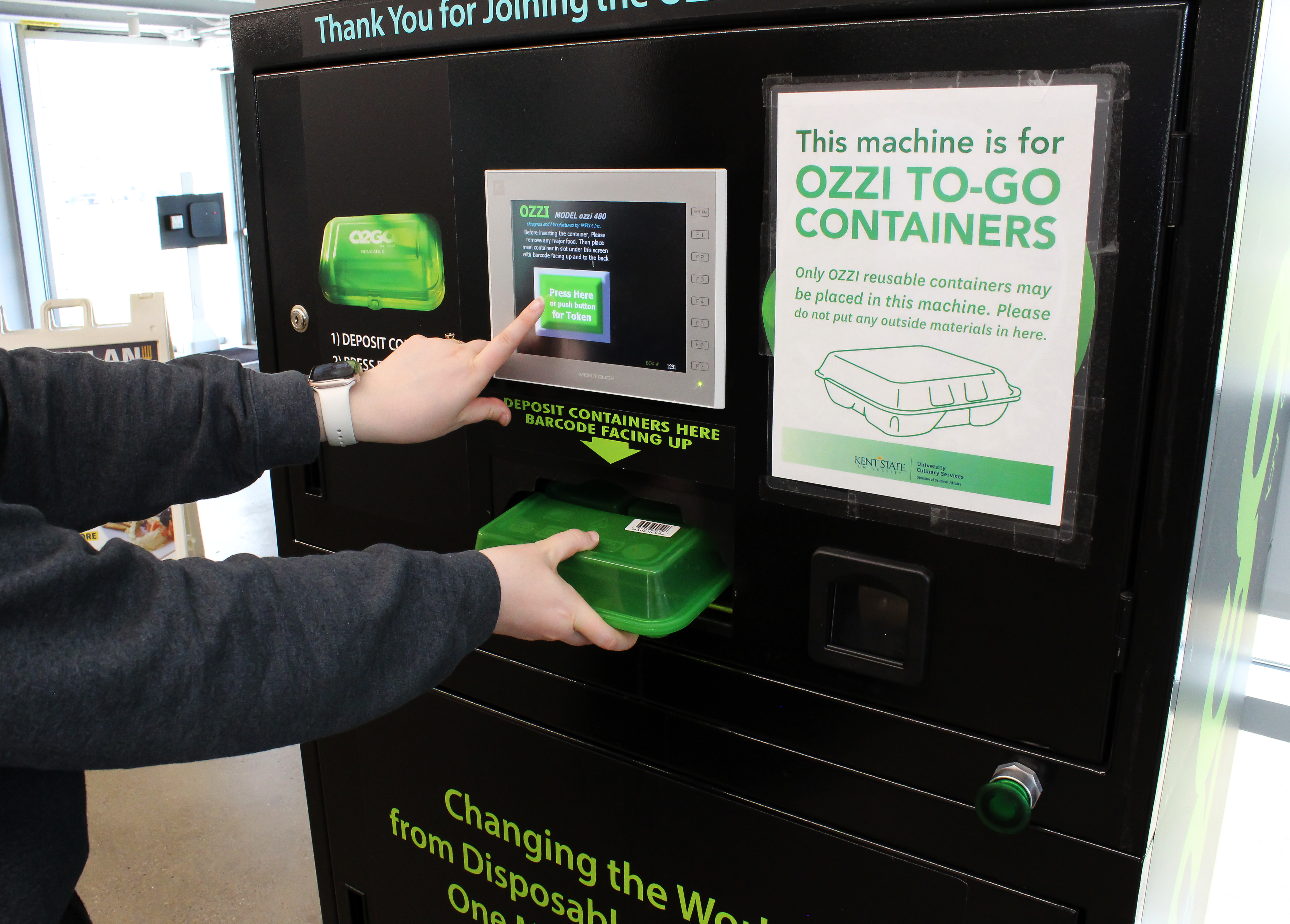 Person inserting an OZZI container into the OZZI machine and pressing the button for a return token