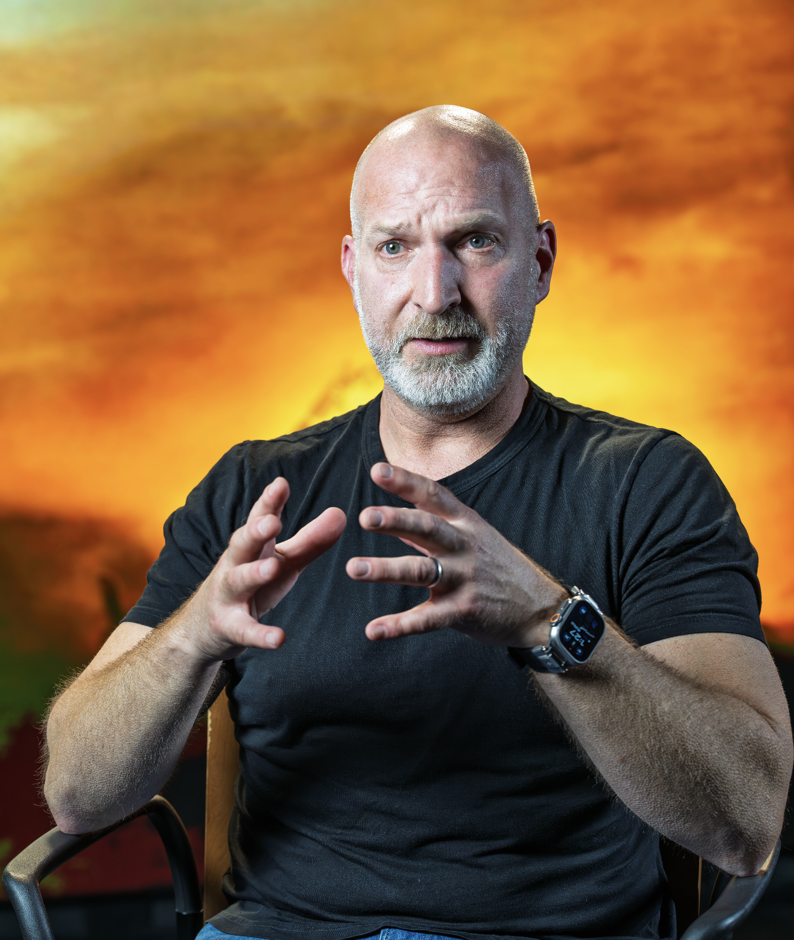 Marcus Lehto seated and speaking energetically, gesturing with his hands, against a vivid background of warm sci-fi colors.