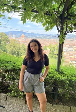 A picture of Maddie Wansack standing on a hill, under a tree overlooking Florence, Italy