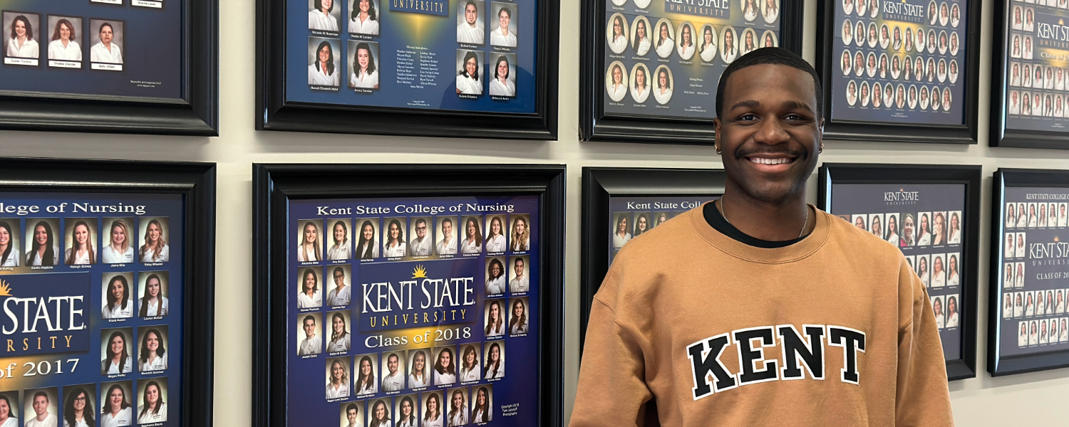 Malcolm Morgan standing in front of nursing graduate composite photos