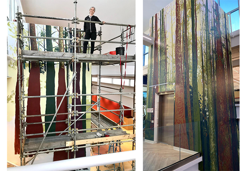 Eileen Dorsey painting an indoor mural of trees.