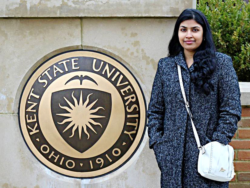 Doctoral student Rashmi Singh standing next to University seal