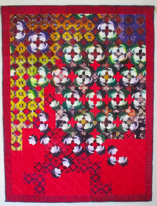 An art quilt composed of solar plate prints, boasting vibrant reds and greens