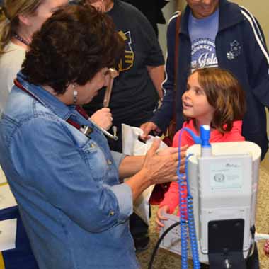 Dr. Mary Lou Ferranto, director of the nursing program, takes the pulse of a young girl.