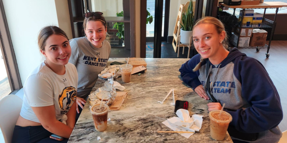 Three students at a table enjoying coffee and bagels