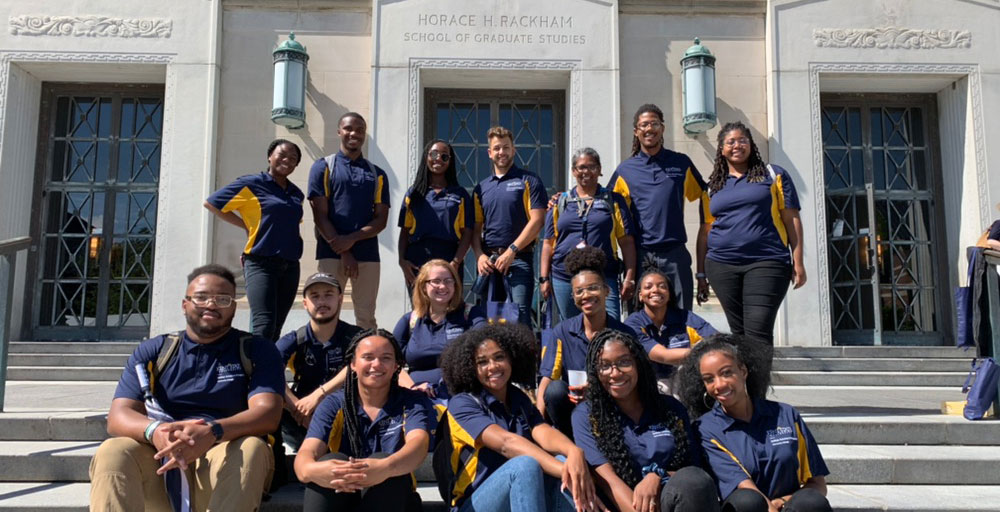 McNair Staff and Scholars sit on the steps of University of Michigan graduate school