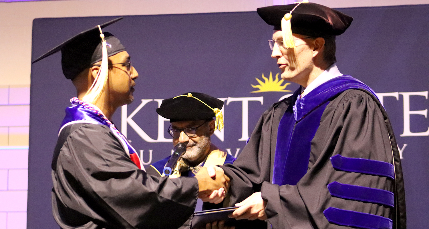 Dean Bill Ayres shakes the hand of a graduating student at commencement