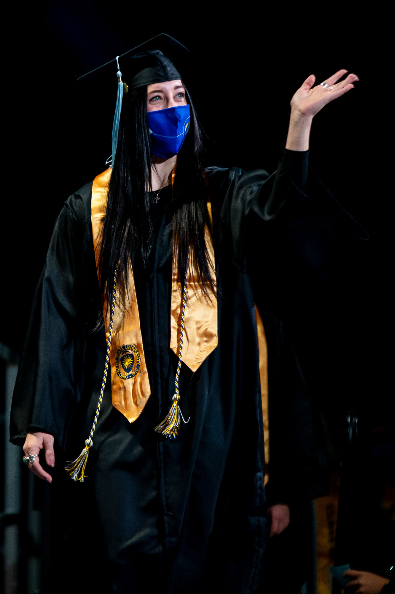 A new Kent State graduate waves to her loved ones as she crosses the stage during her commencement ceremony.