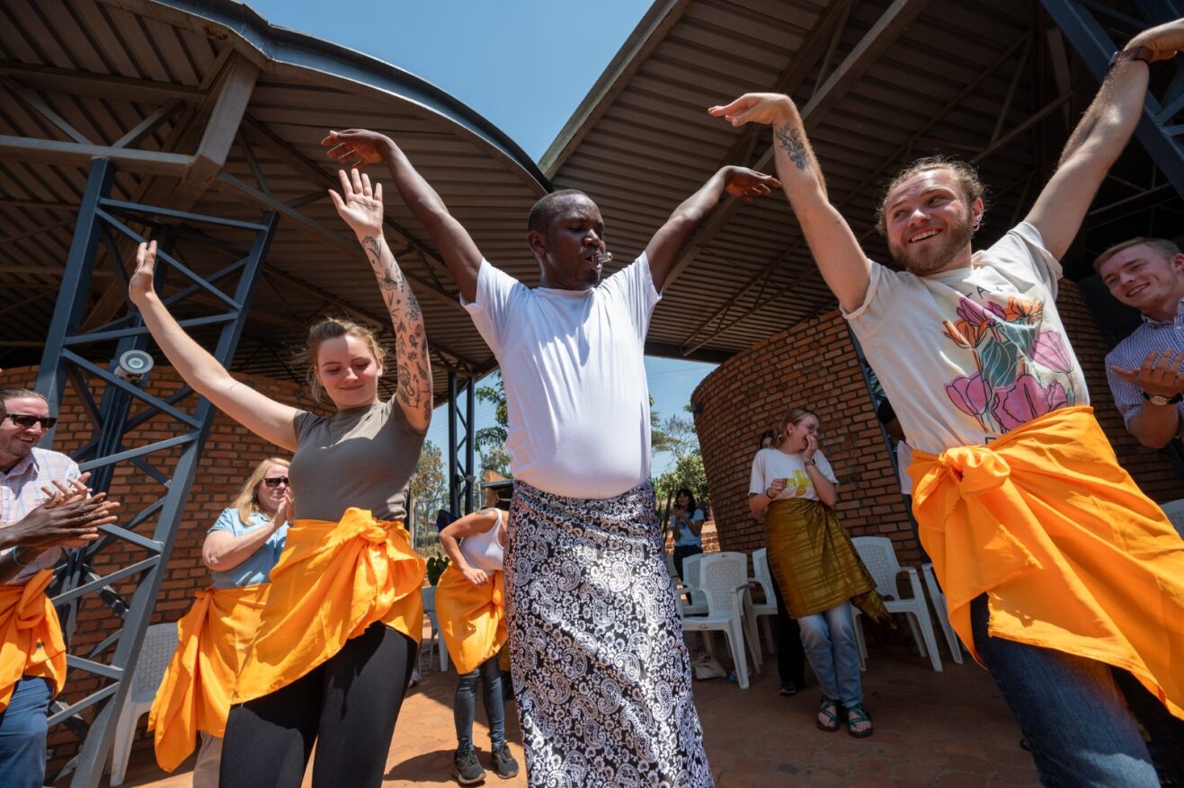 Emily Spencer, left, a student in the Kigali Summer Institute, takes part in a traditional dance performance during a stop at the Urugo Women’s Opportunity Center in Kayonza, Rwanda.