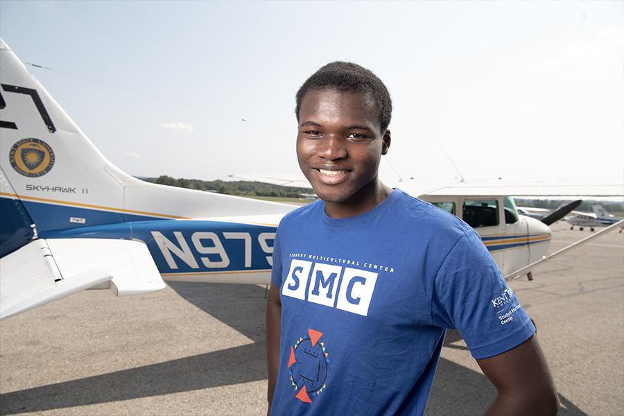 Divine Asante stands in front of a СƬƵ airplane.