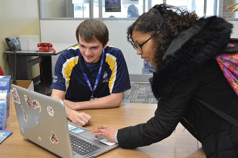 female student gets assistance at the library technology helpdesk