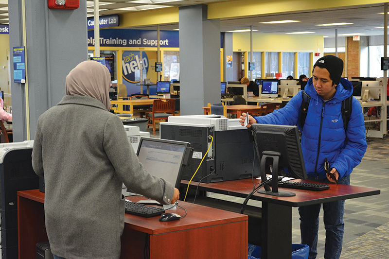 two students using printer stations in the library