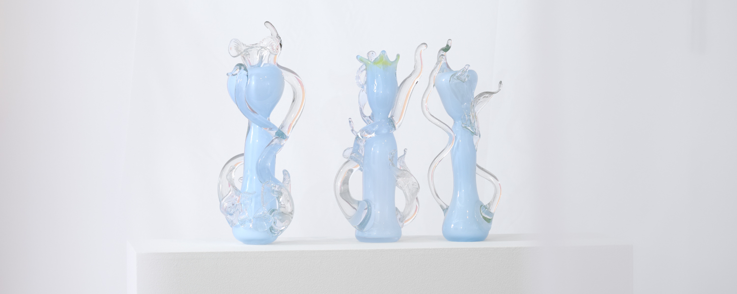 three light blue glass sculptures with clear tendrils on display 