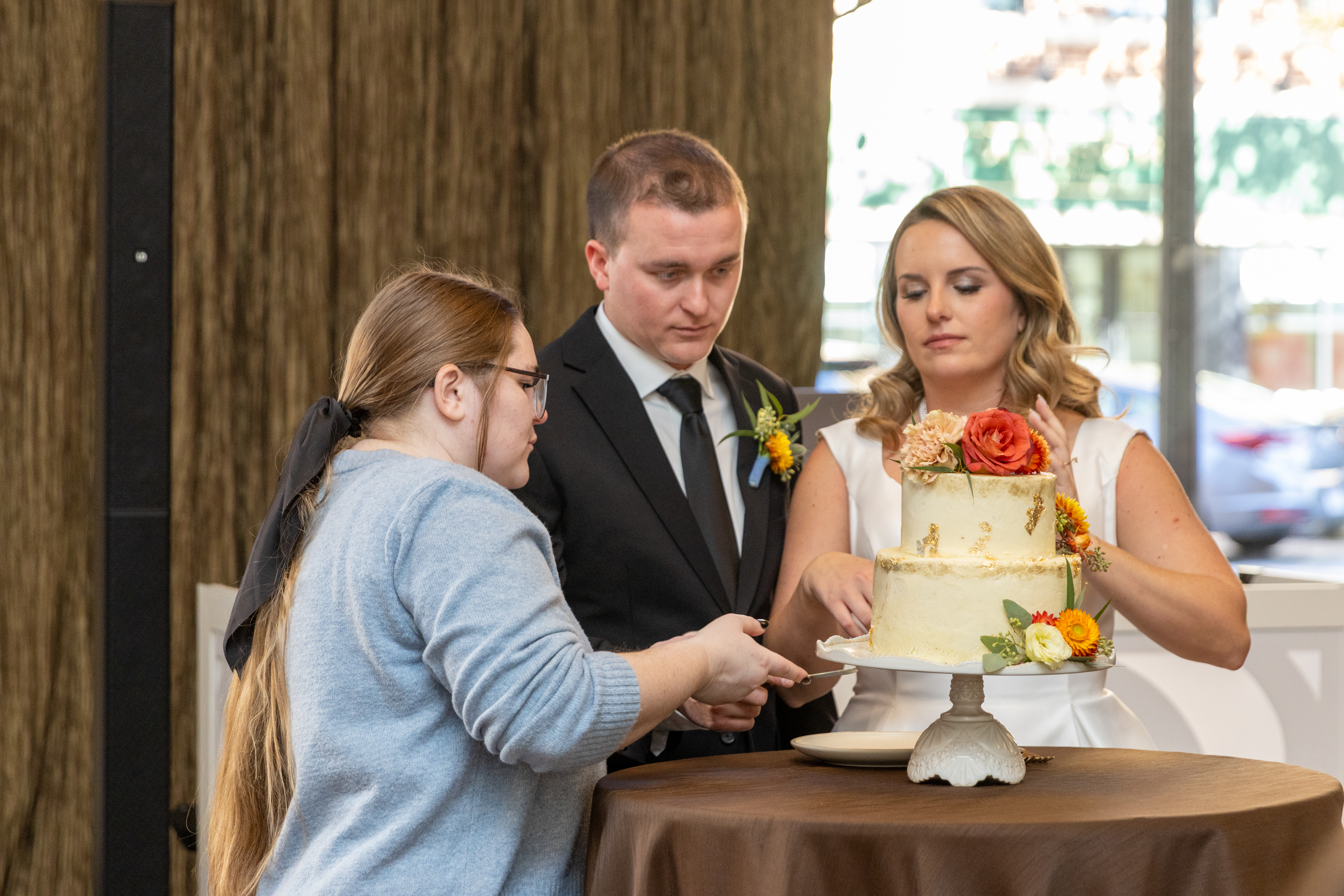 Brooklyn Fockler Leshon assists the bride and groom in staging the cutting of the wedding cake. 