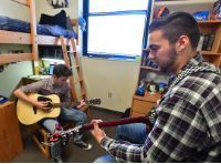 students playing their guitars in a dorm room