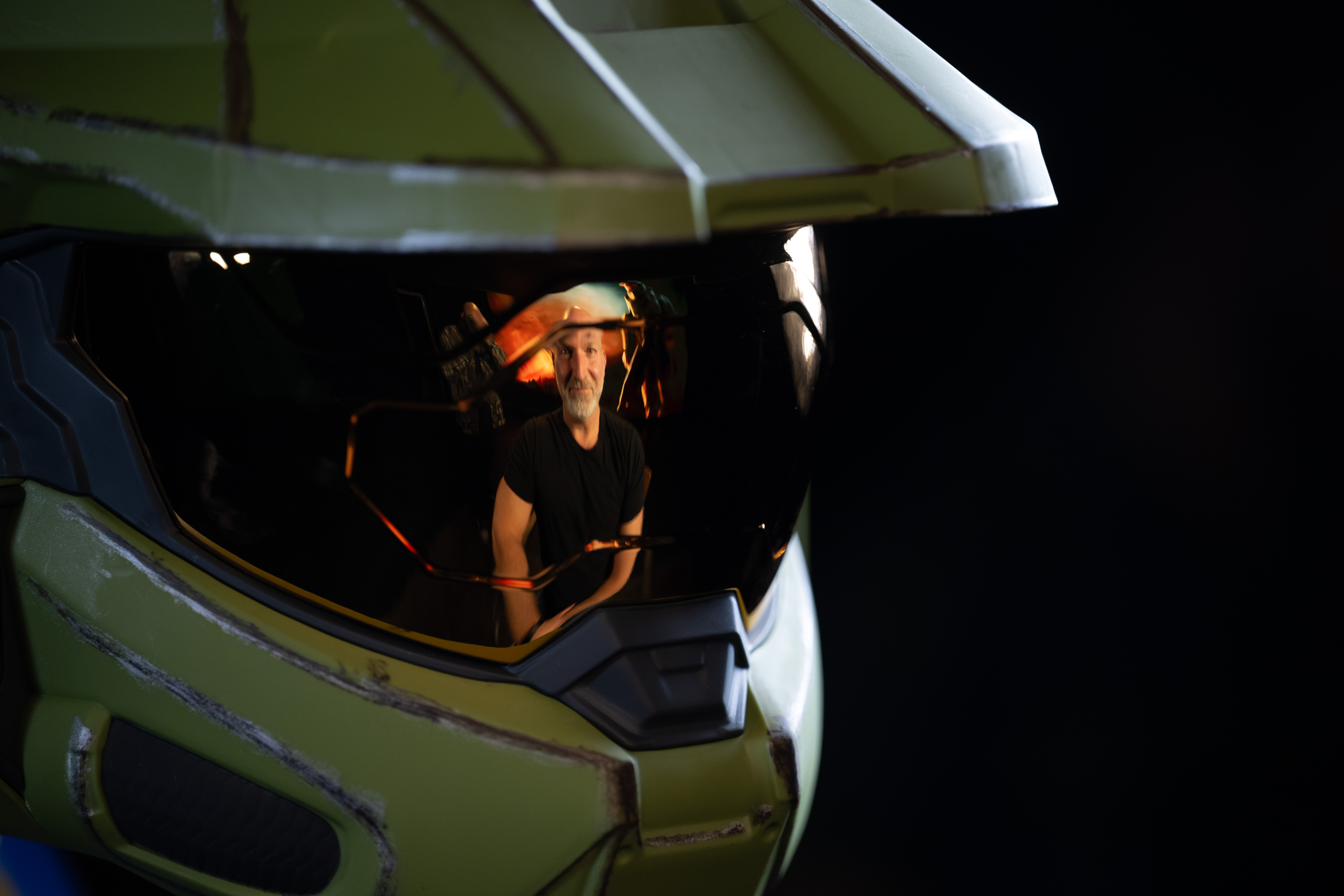 Close-up view of a Master Chief helmet in dramatic lighting, showing the reflection of Marcus Lehto.